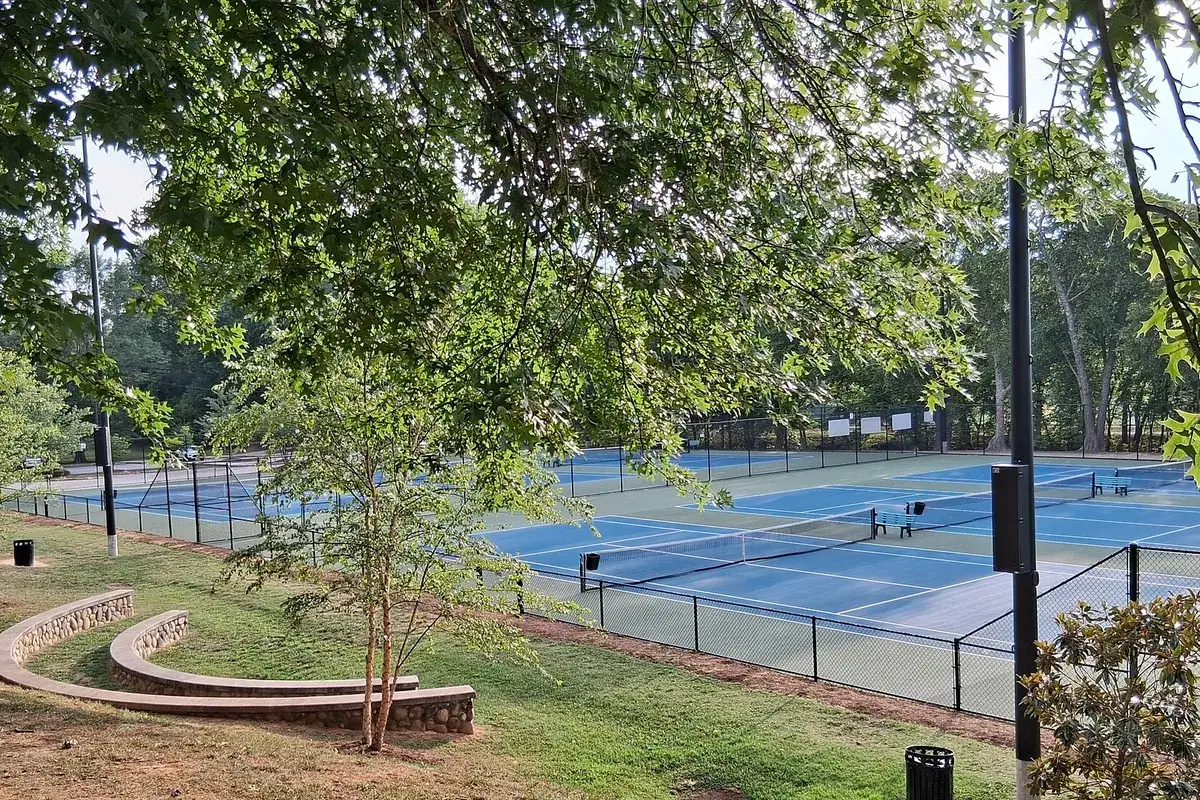 Cụm sân Tennis mặt cứng màu xanh dương giữa khuôn viên cây xanh